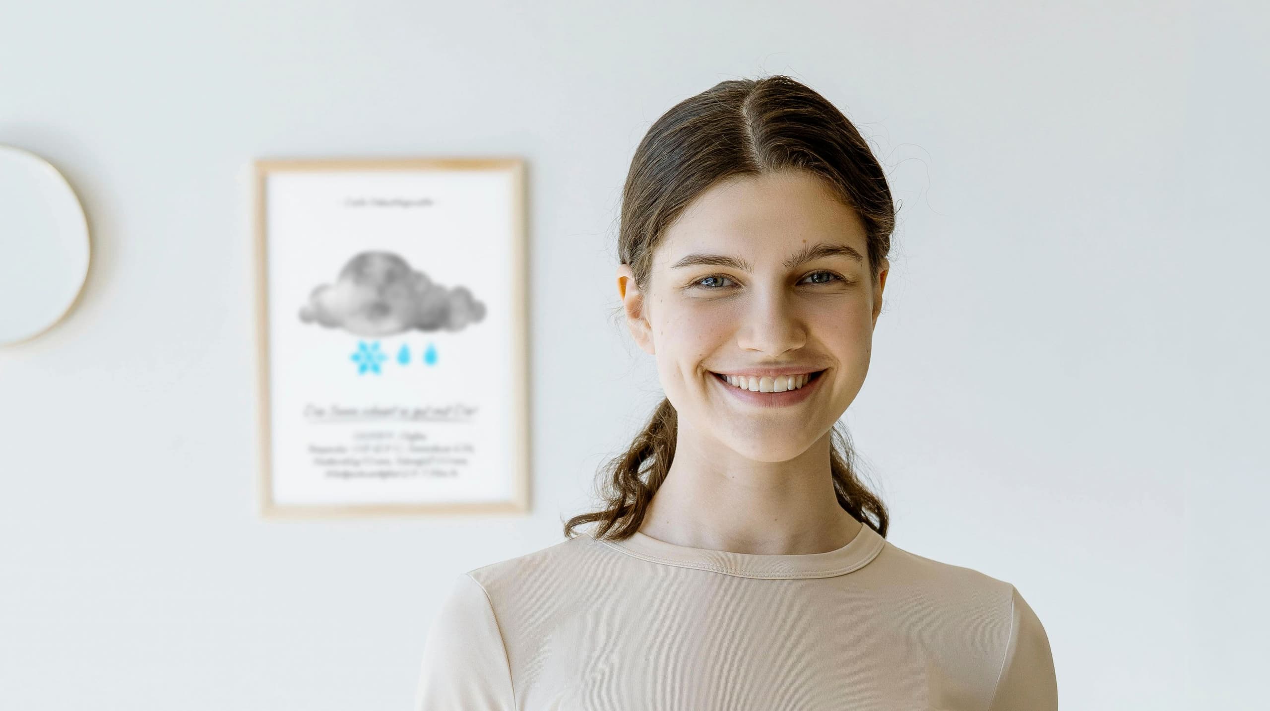 Picture of a young smiling woman in front of a poster with a watercolour rain cloud